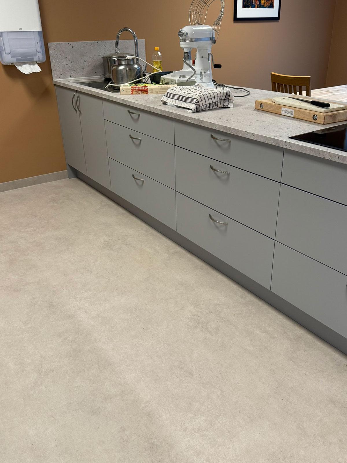 kjøkkenbenk med skuffer i grått med kjøkkenmaskin stående oppå