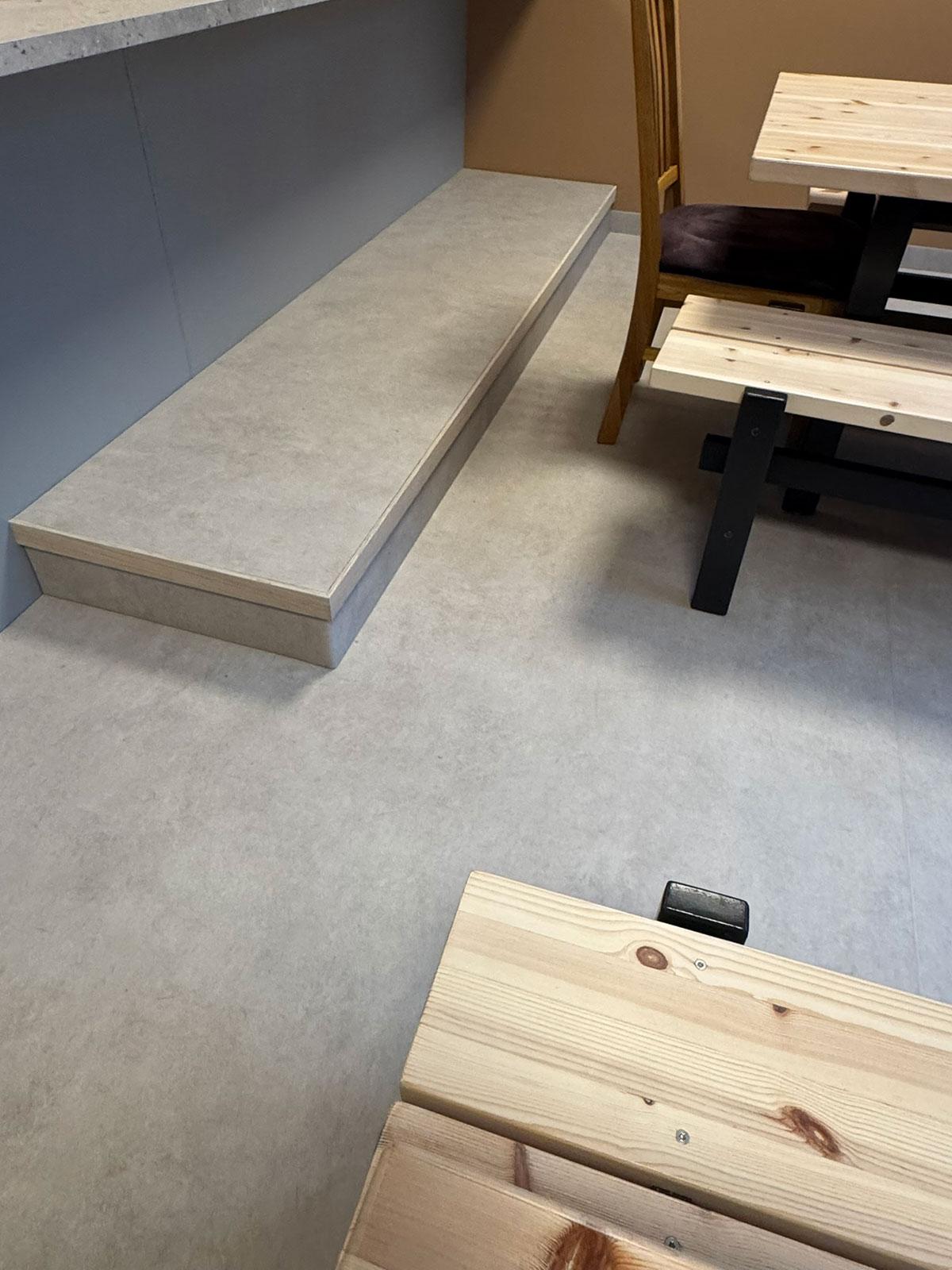 opphøyd gulv under kjøkkenbenk med sittebenker så vidt synlig til høyre i bildet