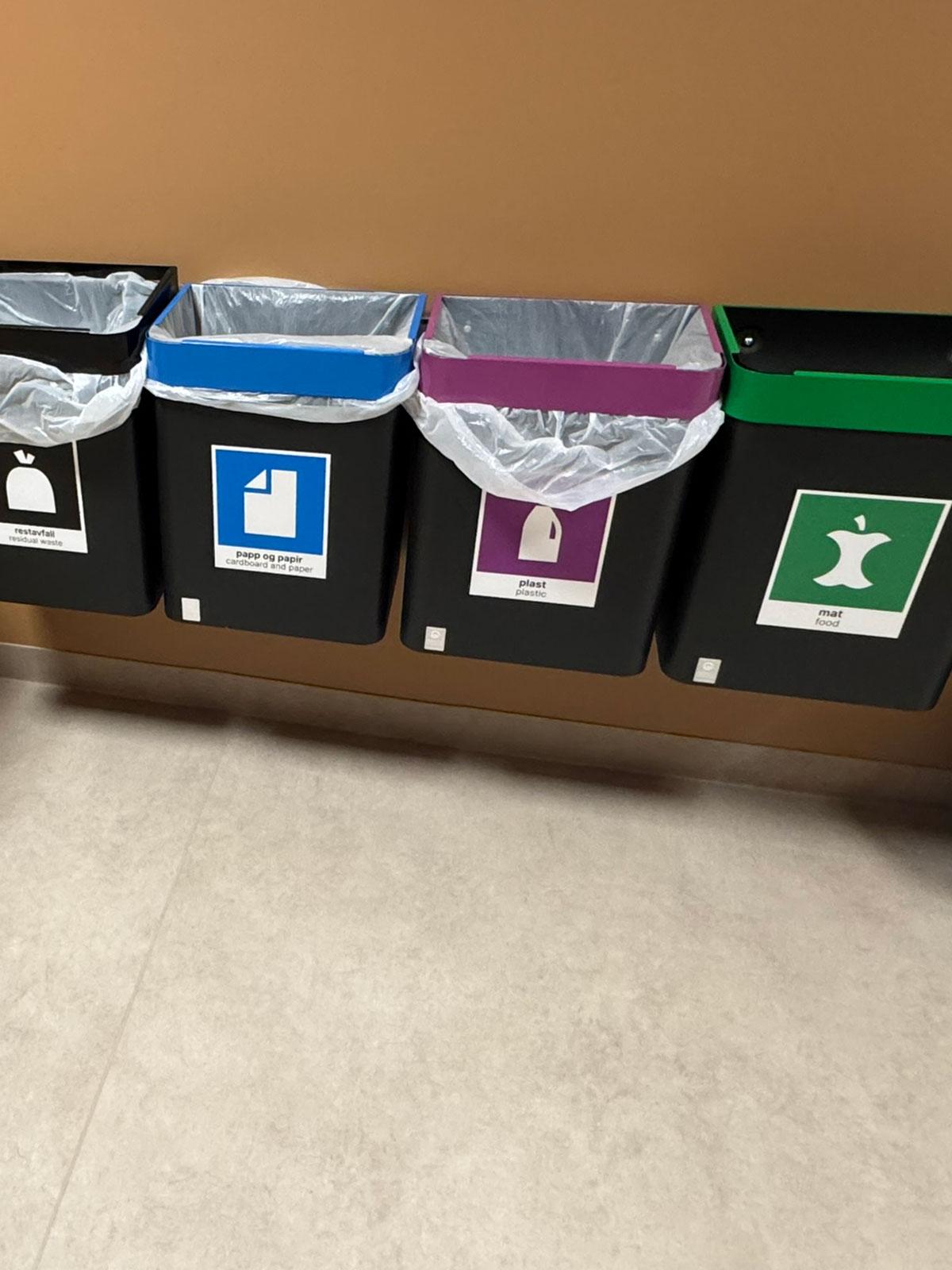 fire bøtter for avfallssortering hengende på en vegg