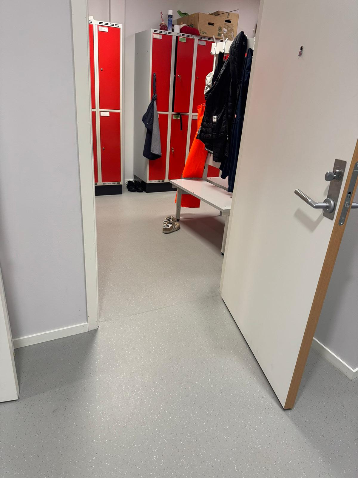 innsyn i en garderobe hvor døren står åpen. I garderoben er det garderobeskap med rød dører og klær hengende på kroker