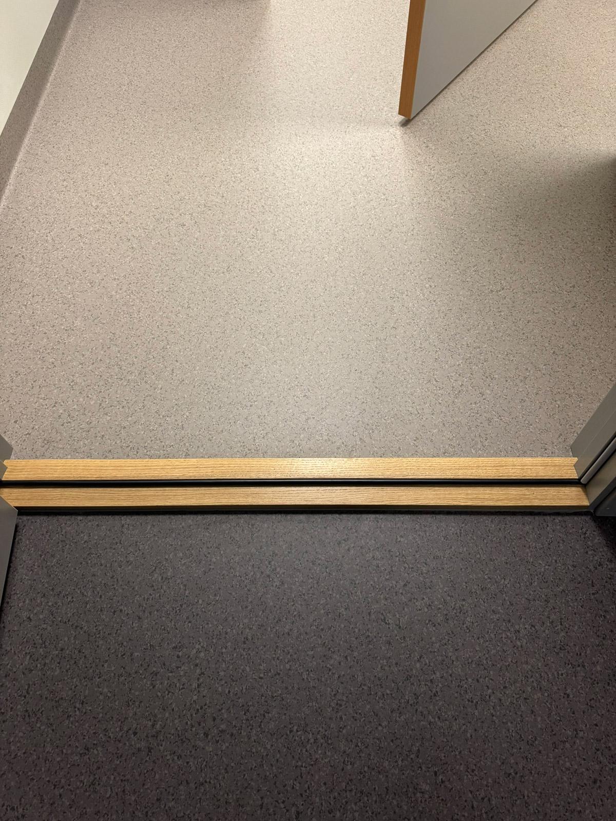 Overgang mellom to typer gulvbelegg med trinnlist i tre på Spicheren treningssenter.